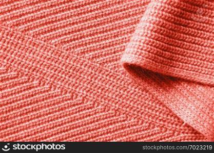 Winter warm scarf clothing background of knitted cotton fabric with folds in a color of the year 2019 Living Coral Pantone.. Background of the knitted fabric in a color of the year 2019 Living Coral Pantone.