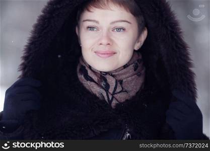 Winter woman in a fur coat on the snow outside