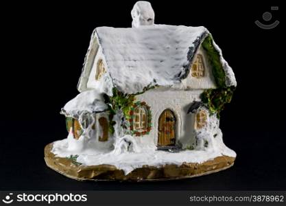 winters christmas decoration with small toy ceramic house over black background