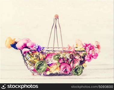 Wire flowers basket with colorful garden flowers , front view, pastel color