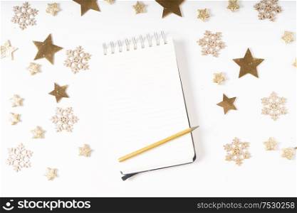Wish list for Cristmas and New Year. Holiday decorations and ruled notebook with wish list on white desk, flat lay over white. Christmas flat lay scene with golden decorations