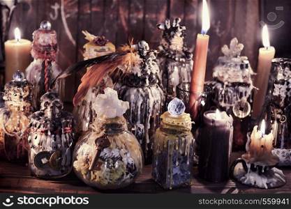 Witch bottles and candles in magic candlelight on the table. Wicca, esoteric, Halloween and occult background with vintage magic objects for mystic rituals