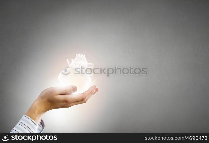 With care and love to your heart. Close up of male hands holding human heart