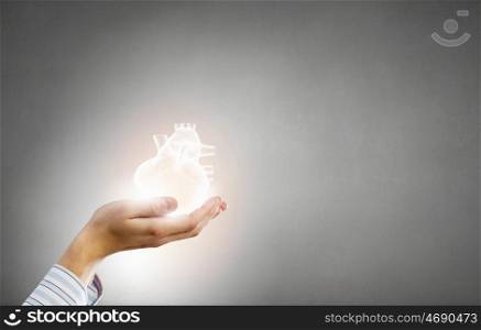 With care and love to your heart. Close up of male hands holding human heart