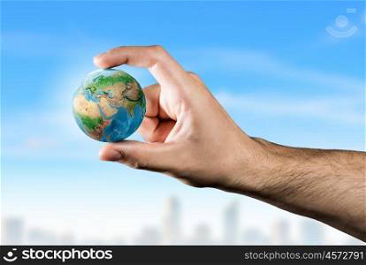 With care to our planet. Small Earth planet between male fingers. Elements of this image are furnished by NASA
