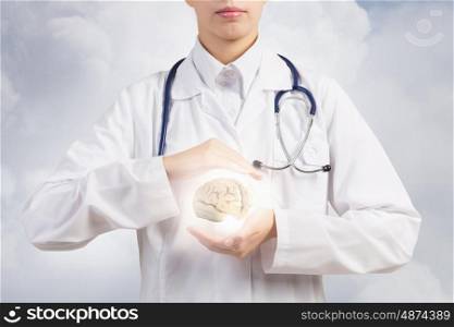 With care to your health. Woman doctor in white holding human brain in palms