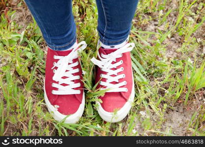 With red sneakers and jeans in the field treading the grass