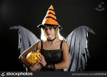 Withch woman dress for halloween with orange hat and pumpkin. Dark make-up