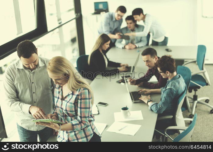 wo business people using tablet preparing for next meeting and discussing ideas with colleagues in the background