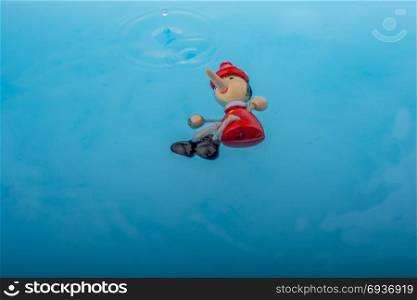 Wodden puppet Pinocchio on in blue water