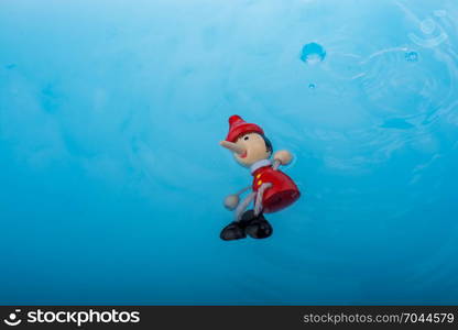 Wodden puppet Pinocchio on in blue water