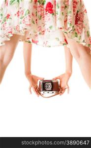 Woman&#39;s legs and hand, unusual back view of girl taking picture using vintage camera isolated on white background