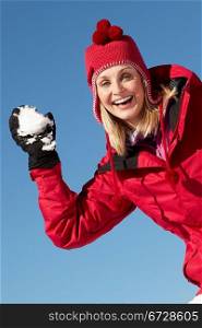 Woman About To Throw Snowball Wearing Warm Clothes On Ski Holiday In Mountains