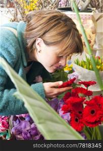 Woman absorbing the scent of a flower whilst shopping at a florist