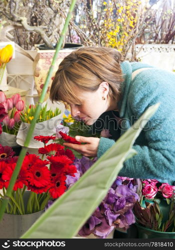 Woman absorbing the scent of a flower whilst shopping at a florist