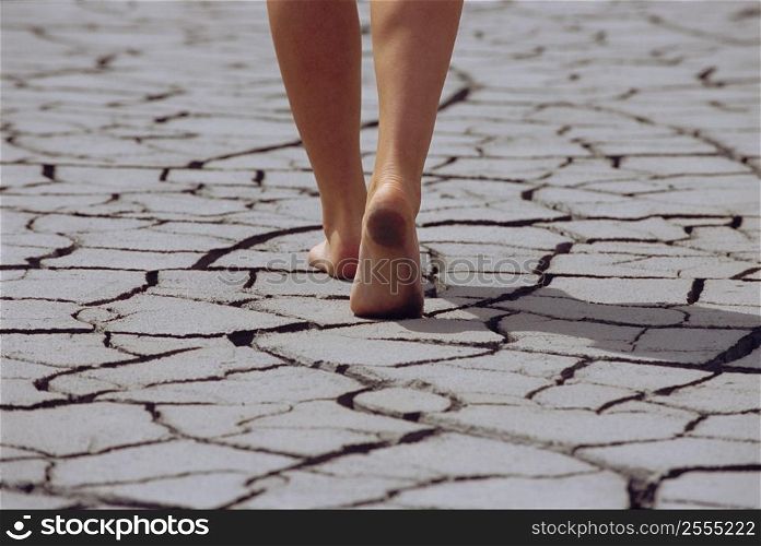 Woman&acute;s feet walking over cracked earth