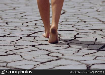 Woman&acute;s feet walking over cracked earth