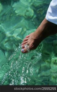 Woman&acute;s foot outdoors dipping into water (selective focus)