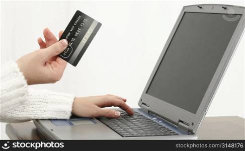 Woman&acute;s hand at table with Gold Card and Laptop computer. Shopping or Paying Bills. Shot in studio.