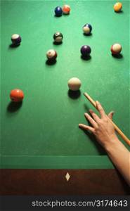 Woman&acute;s hand preparing to hit pool ball while playing billiards.