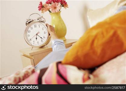 Woman&acute;s hand reaching for an alarm clock
