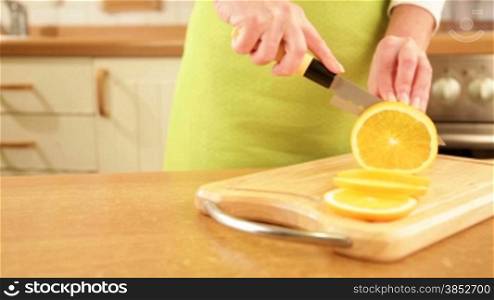 Woman&acute;s hands cutting orange