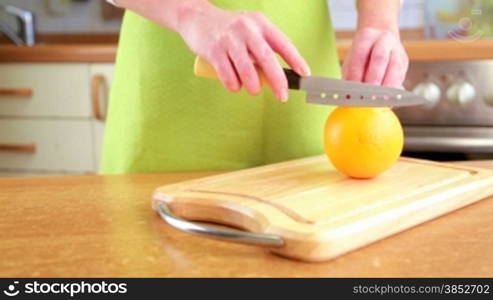 Woman&acute;s hands cutting orange