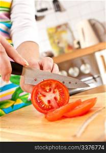 Woman&acute;s hands cutting tomato, a sharp knife.