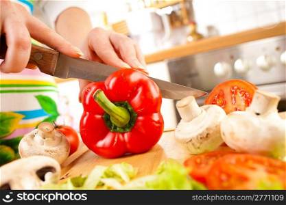 Woman&acute;s hands cutting tomato bell pepper, behind fresh vegetables.