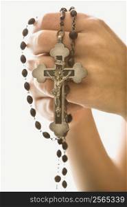 Woman&acute;s hands holding rosary with crucifix.