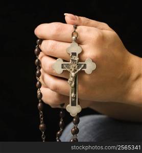 Woman&acute;s hands holding rosary with crucifix.