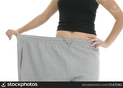 Woman&acute;s torso holding out super huge sweat pants to show of weight loss. Shot in studio.