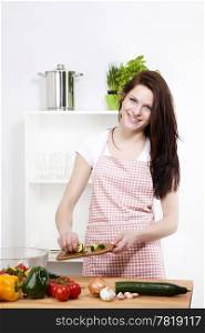 woman adding cucumber to her salad. happy woman in kitchen adding cutted cucumber to her salad