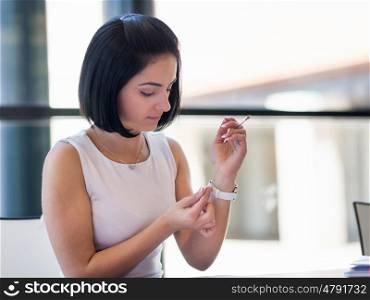 Woman adjusting at her watch. Woman in white dress putting on her watch