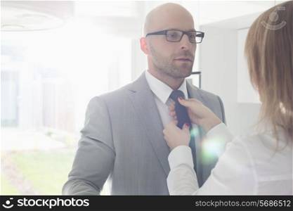Woman adjusting businessman&rsquo;s tie at home