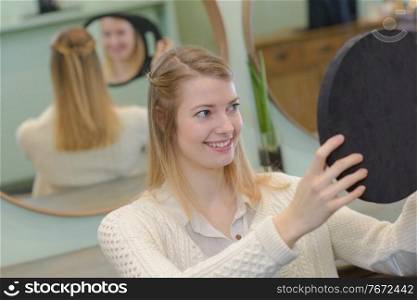 Woman admiring hairstyle in mirror