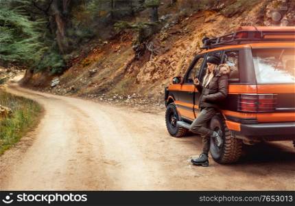Woman adventurer traveling and exploring mountainous off-road destinations, road trip, texting using her mobile phone