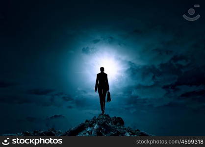 Woman against bright light. Rear view of businesswoman standing on top and looking in sky