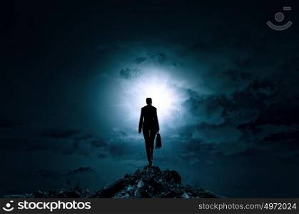 Woman against bright light. Rear view of businesswoman standing on top and looking in sky