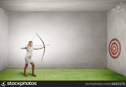 Woman aiming her goal. Young woman archer in suit aiming to make shoot