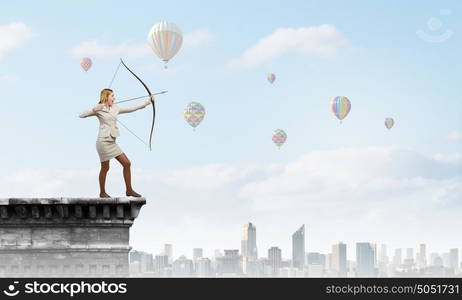 Woman aiming her goal. Young woman archer in suit aiming to make shoot