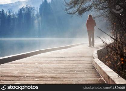 woman alone by lake on foggy sunrise in autumn