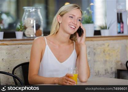 woman alone in cafe taking a call on her smartphone