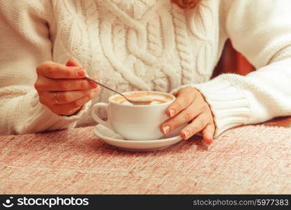 Woman&amp;#39;s hands holding mix cappuccino on the table. Close-up