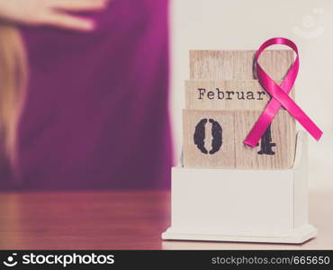 Woman and calendar, it is 4 february world breast cancer day, date with pink awareness ribbon. Healthcare and medicine concept.. Woman and world breast cancer day on calendar