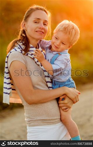Woman and child having fun outdoors in sunset sunlight. Happy woman and child having fun outdoors. Family lifestyle rural scene of mother and son in sunset sunlight.