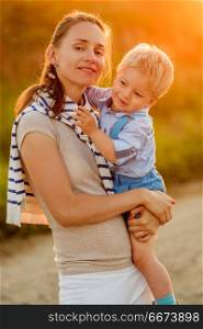 Woman and child having fun outdoors in sunset sunlight. Happy woman and child having fun outdoors. Family lifestyle rural scene of mother and son in sunset sunlight.