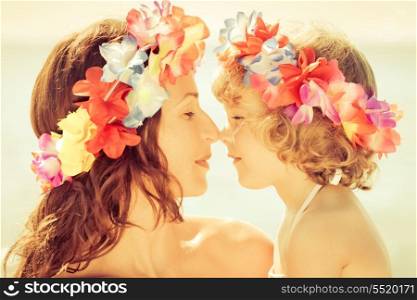 Woman and child wearing hawaiian flowers garland on the beach. Summer vacations concept