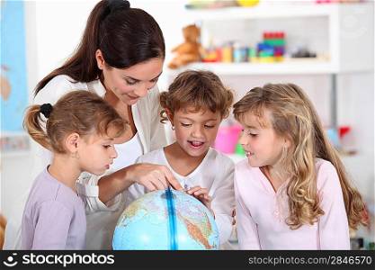 woman and children looking at a terrestrial globe
