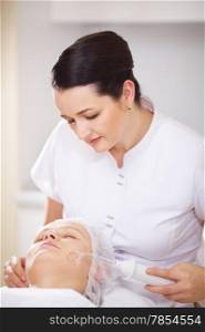 Woman and cosmetician during facial spa procedure in the beauty treatment salon